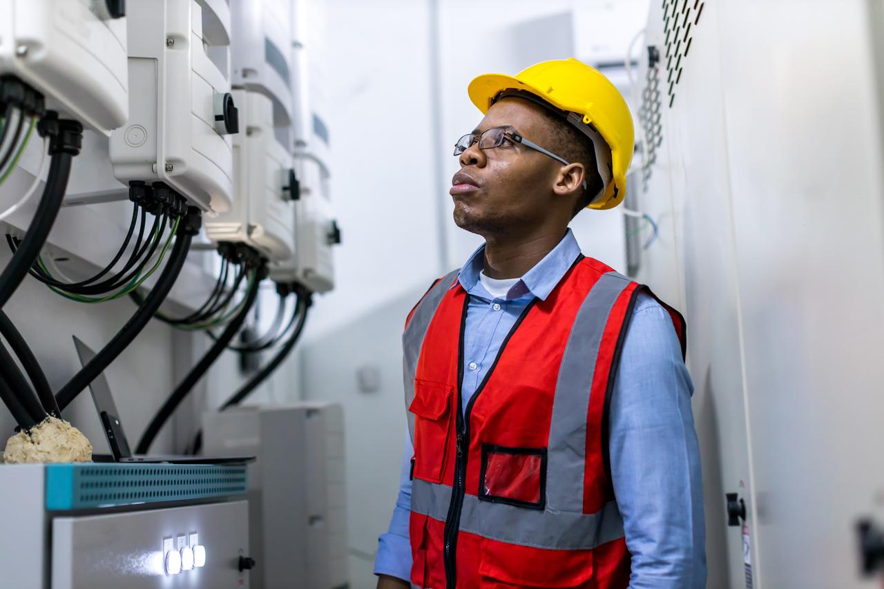 Engineer in a hard hat inspecting electrical switchgear